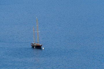 Old wooden sailboat anchored in the distance