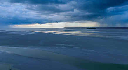 Dramatic tidal zone panorama with rain approaching on the horizon during early evening light