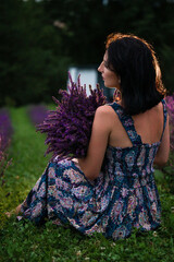 Woman in floral dress holding lavender in a field.