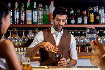 A charismatic bartender or mixologist smiles at a customer while preparing a craft cocktail with a shaker A concept for the hospitality industry and expert service