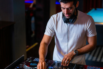 A professional DJ mixes a live set on a controller in a dark nightclub or bar A concept for...