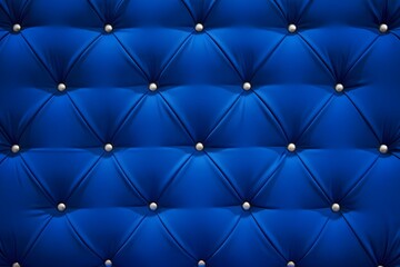 A close-up, full-frame view of a rich royal blue tufted upholstery. The material features a classic diamond pattern created by deep folds and secured with polished silver studs.