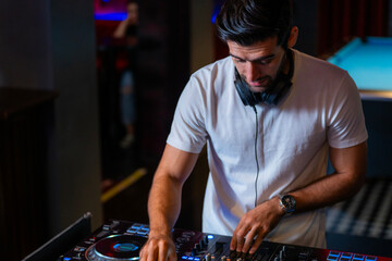 A professional DJ mixes a live set on a controller in a dark nightclub or bar A concept for...