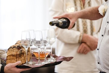 Pouring sparkling wine into champagne flutes, next to a loaf of bread and honey.