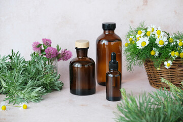 Three dark glass bottles containing essential oils arranged with vibrant herbs and blooming...