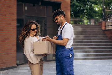 Delivery courier holding mobile phone for woman receiving package
