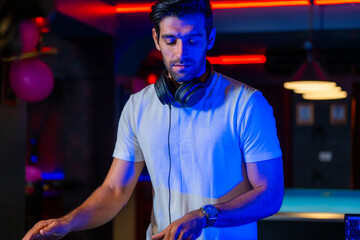 A professional DJ mixes a live set on a controller in a dark nightclub or bar A concept for...