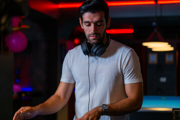 A professional DJ mixes a live set on a controller in a dark nightclub or bar A concept for...