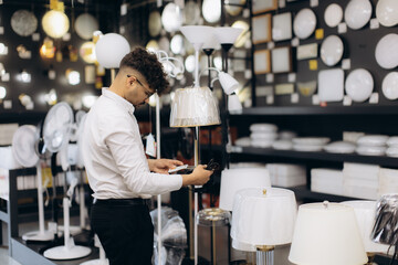Young Man Shopping for Lamps in a Lighting Store Interior