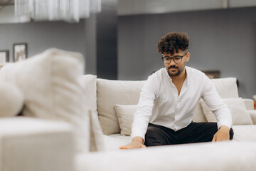 Man Testing Sofa Texture in a Modern Furniture Store Interior
