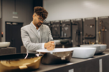 Man in Suit Evaluating Various Bathroom Sinks in a Modern Showroom