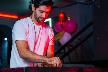 A professional DJ mixes a live set on a controller in a dark nightclub or bar A concept for...