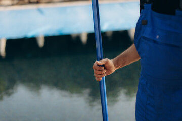 Pool cleaner holding telescopic pole by the poolside: ready for cleaning