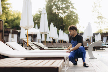 Hotel worker arranging sunbeds by the poolside with umbrellas