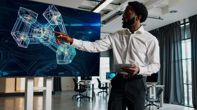 A professional presenting futuristic 3D models on a screen, captured from a side angle. The video conveys innovation and technology in a modern office.