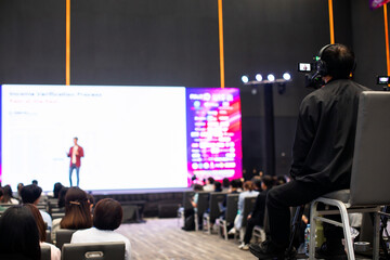 selective focus to cameraman with blurry video camera set are recording to speaker and audience in conference hall or seminar event. exhibition convention center.