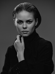 black and white portrait of a serious woman with intense gaze wearing dark clothing and touching...