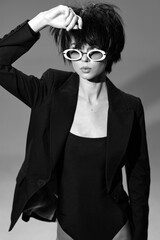 stylish woman in black blazer and sunglasses poses confidently with tousled hair in a monochrome...