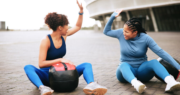 Fitness, workout and women with high five in city for strength training, teamwork or performance. Ground, friends or celebration with medicine ball for exercise support, achievement or wellness goals - Powered by Adobe