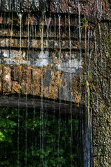 Falling water on the old brick wall of an ancient building.