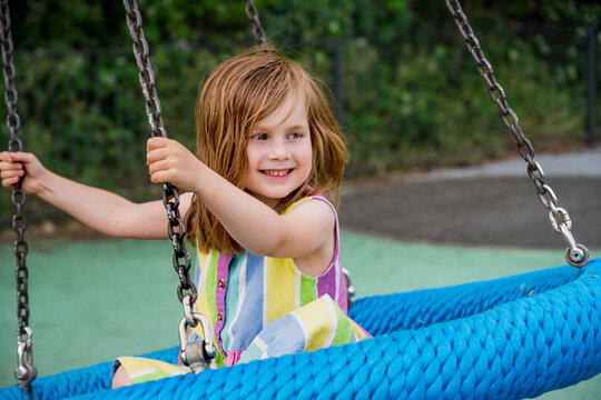 Smiling little girl at playground. Toddler child having fun at a swing