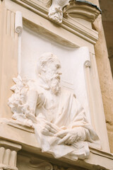 Fototapeta premium Marble bust of bearded man holding book on historic stone wall