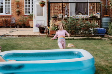 Child girl running to the pool in backyard.