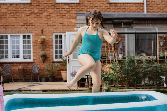 Child girl jumping into inflatable pool