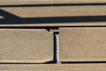 Damaged composite decking boards due to incorrect installation. Close-up of cracked and misaligned...