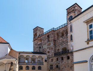 Inner courtyard of Sárospatak Castle in Hungary with Renaissance arcades, clock tower, and old stone walls under clear blue sky.