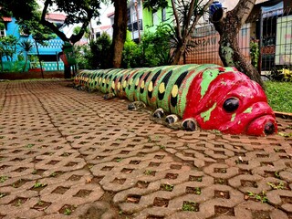 Painted used tires shaped like a colorful caterpillar with many legs, arranged creatively in an outdoor area for decoration or kids' playground.