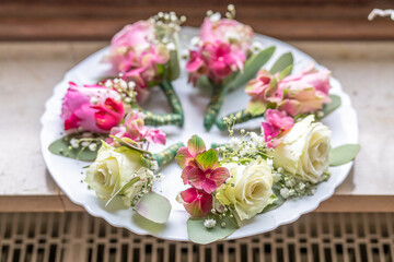 Small stylish boutonnieres on white marble plate, flat lay colorful many groom