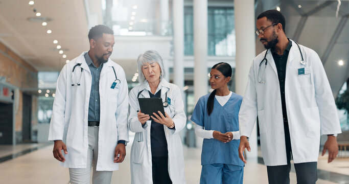 Doctor, woman and tablet with team in lobby with discussion, review and medical research at clinic. People, mature leader and group with tech, feedback and report with healthcare services at hospital - Powered by Adobe