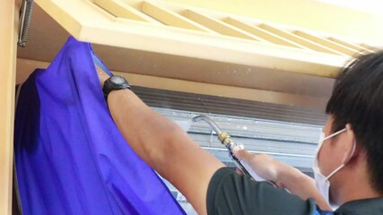Air- con technician using high pressure water gun for cleaning air conditioner