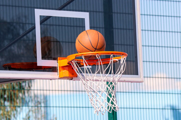 A basketball is sitting on the rim of a basketball hoop