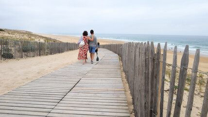 couple walking wooden path at ocean atlantic coast acess sea beach sand dunes with water view