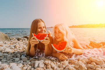 Watermelon Beach Summer: Two women enjoy refreshing watermelon slices on a sunny beach during...