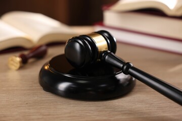 Judge's gavel and books on wooden table indoors, selective focus