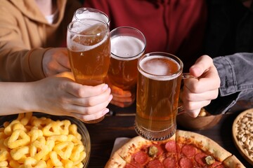 Friends with beer and snacks at wooden table, closeup