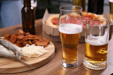 Beer and snacks on wooden table indoors, closeup