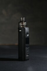 One electronic smoking device on dark table against grey background, closeup