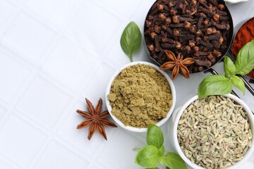 Different aromatic spices on white tiled table, flat lay. Space for text