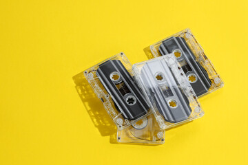 Audio cassettes with magnetic tapes on yellow background, above view. Space for text