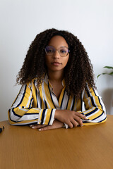 Black woman looking at camera with serious expression during video call. Phone screen view....