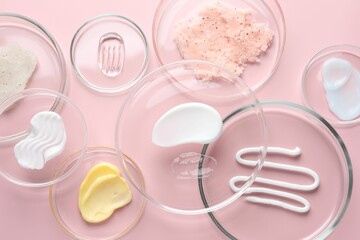 Different cosmetic products in Petri dishes on pink background, flat lay