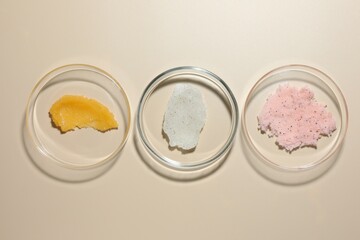 Different cosmetic products in Petri dishes on beige background, flat lay