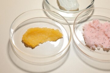 Different cosmetic products in Petri dishes on beige background, closeup