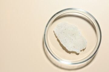 Cosmetic product in Petri dish on beige background, top view. Space for text