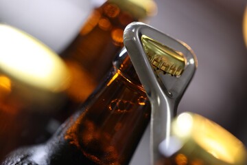 Opening bottle of beer on blurred grey background, closeup