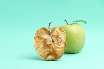 Spoiled apple and good ones on turquoise background